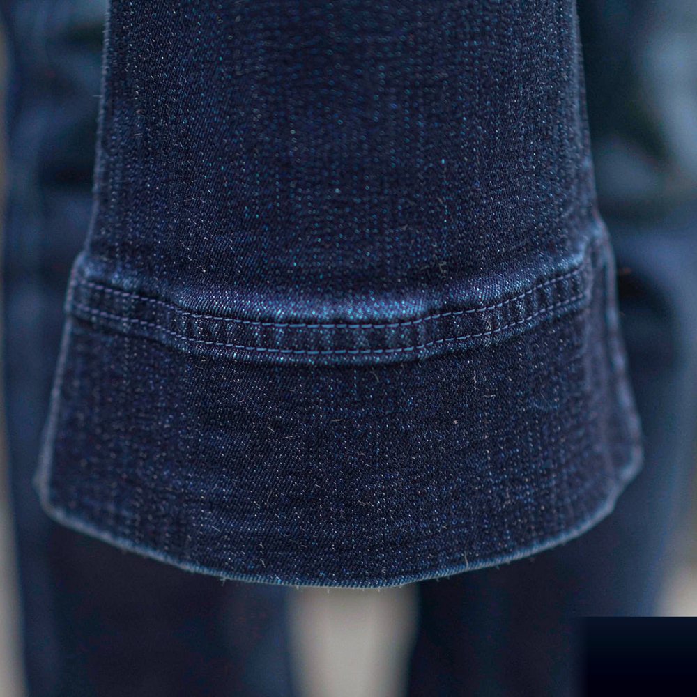 The Bootcut Jean — Deep Indigo Close detail of The Bootcut Jean — Deep Indigo — stitching, hardware and denim weave