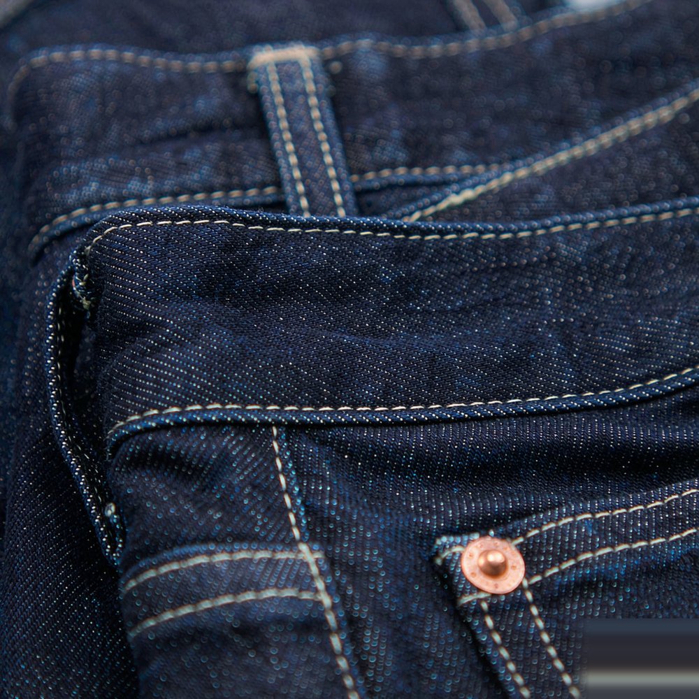 The High Waisted Straight Jean — Raw Indigo Close detail of The High Waisted Straight Jean — Raw Indigo — stitching, hardware and denim weave