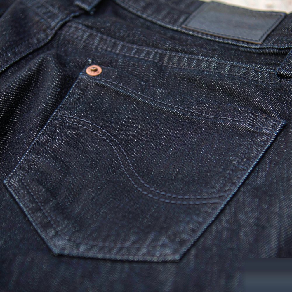 The Mid-Rise Skinny Jean — Dark Indigo Close detail of The Mid-Rise Skinny Jean — Dark Indigo — stitching, hardware and denim weave